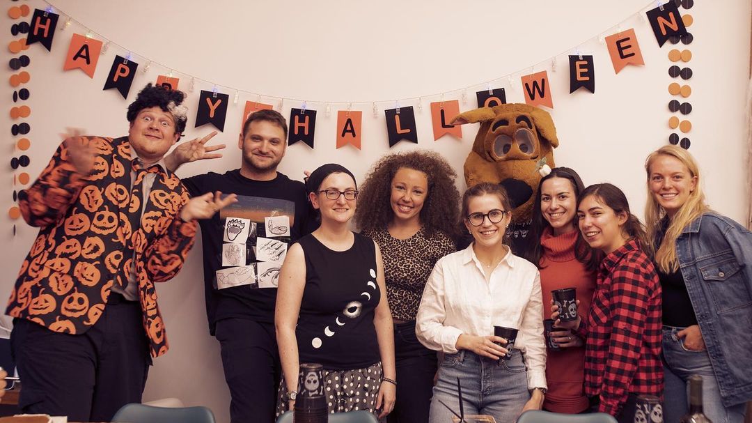 3Play employees stand in costumes under a Happy Halloween banner.