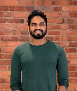 Neel poses smiling in a green longsleeve shirt.