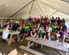 A large group of costumed employees are gathered under a tent, showing various ASL hand signs (mostly saying, I love you!)